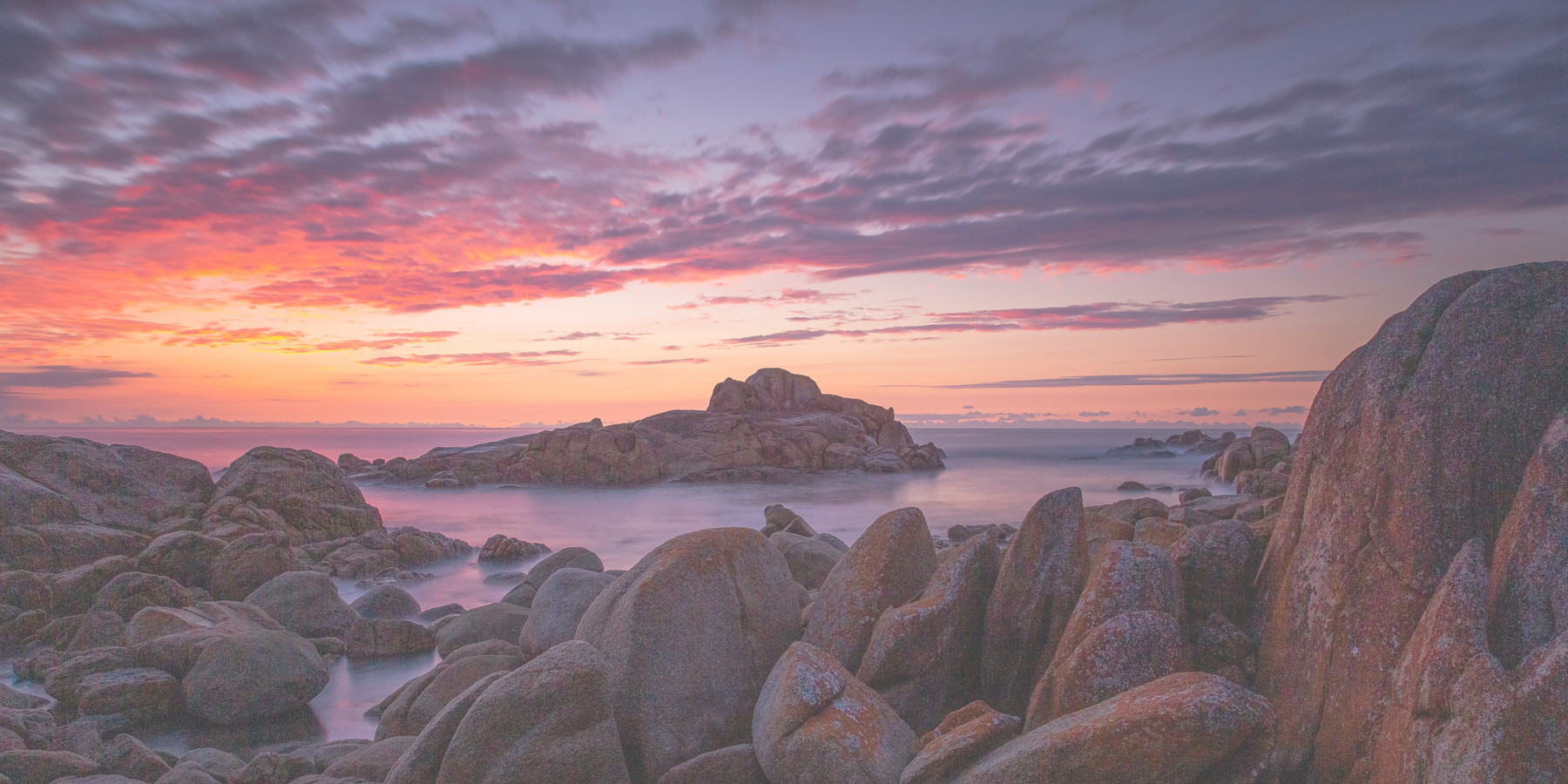 Waves washing over granite boulders on a rugged coastline