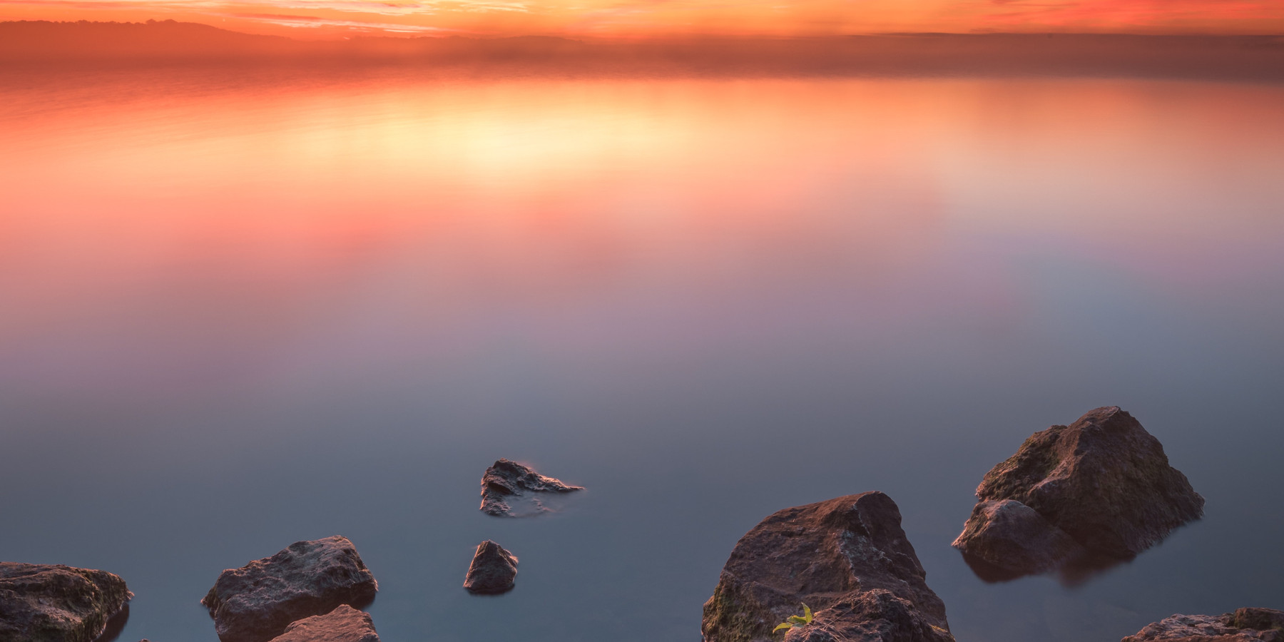 Soft light spreading across still water at dawn